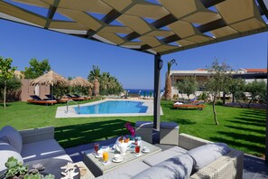 Relax by the pool surrounded by lush greenery and a Mediterranean-style building in the background.