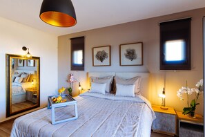 A modern bedroom with a large bed, bedside tables, a mirror, and artwork on the walls.