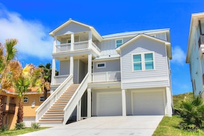 Ein zweigeschossiges Haus mit Balkon, Treppe und Garage.