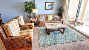 A living room with a sofa, a coffee table, a lamp, and a ceiling fan.