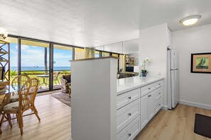 Une cuisine moderne avec vue sur l’océan, un plancher en bois et un coin repas comprenant une table et des chaises.
