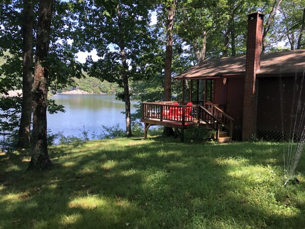 Un chalet au bord du lac, doté d’une terrasse en bois et d’une cheminée en briques.