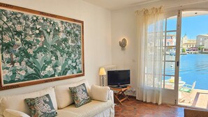 A living room with a sofa, a television, and a large floral painting on the wall.