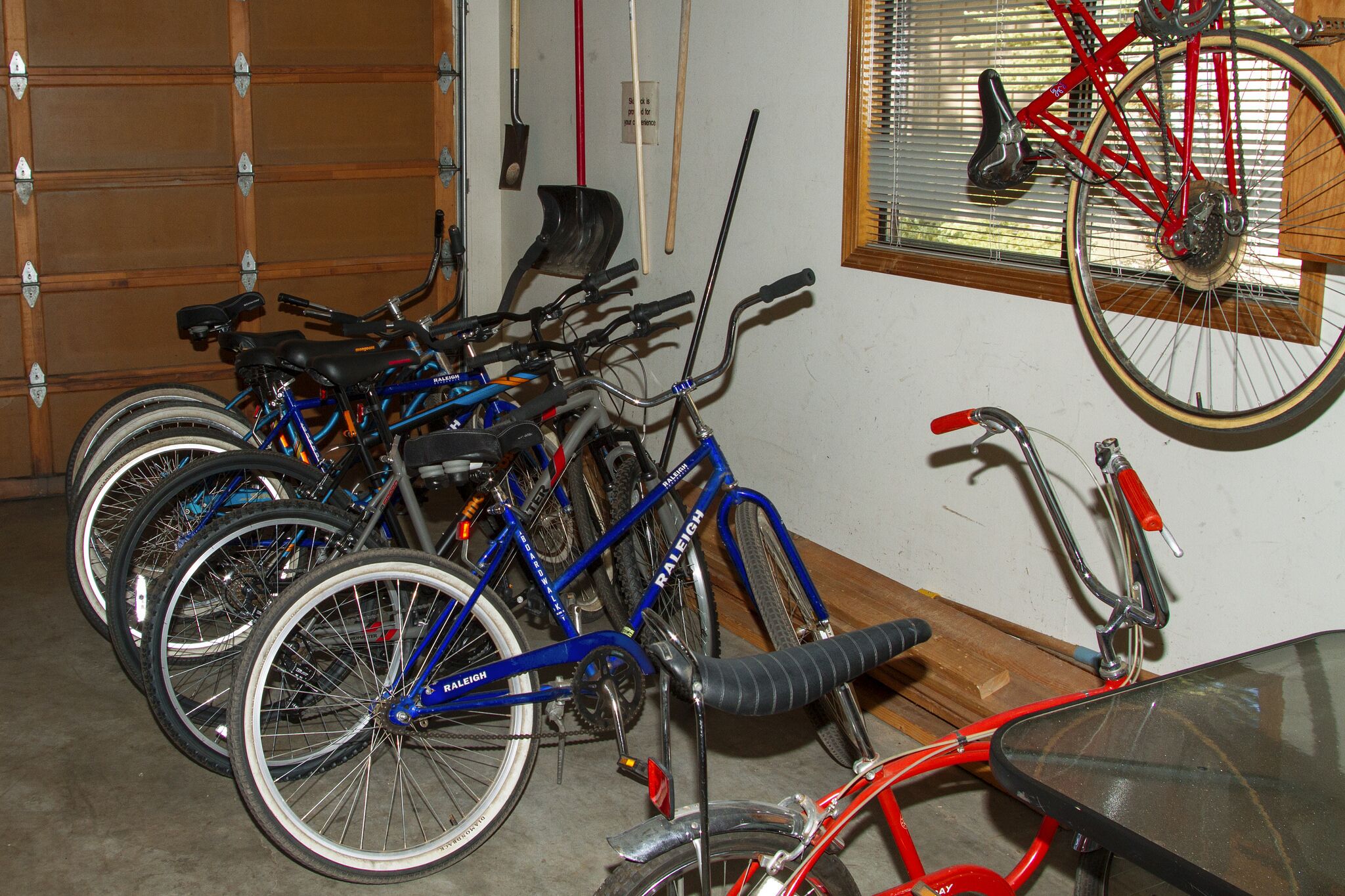 Een garage met fietsen langs de muur en een raam met zonwering.