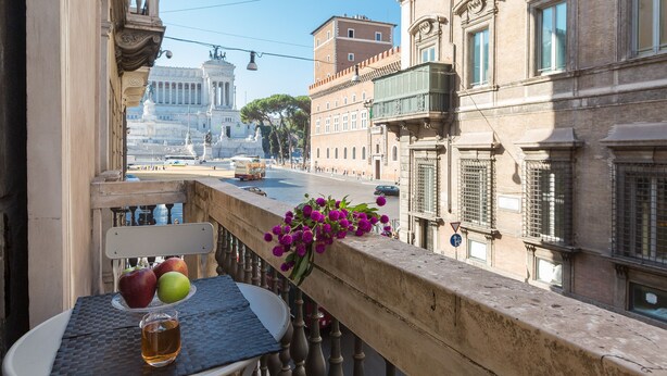 A balcony with a table, a chair, and a vase of flowers. - Amazing Piazza Venezia Suite Int 5 (Roma)
