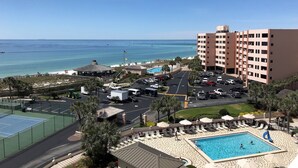 Um hotel com piscina, vista para a praia e área de estacionamento.