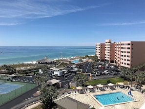 A hotel with a swimming pool, beach view, and parking area.
