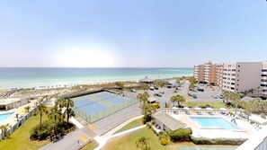 A resort with a tennis court, swimming pool, and beach view.