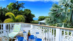 A patio with white metal chairs and tables, blue bowls, and a bottle of wine. - 2nd House from the Beach with No Roads to Cross (Anna Maria)