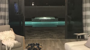 Un salon moderne avec vue sur un espace de bien-être comprenant une piscine et un sauna.