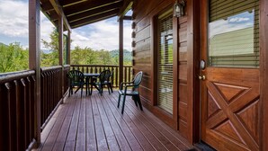 A wooden deck with a table and chairs, a door, and a view of trees and mountains. - ERN849- Sweet Escape - Great Location! Close To Action! (Pigeon Forge)