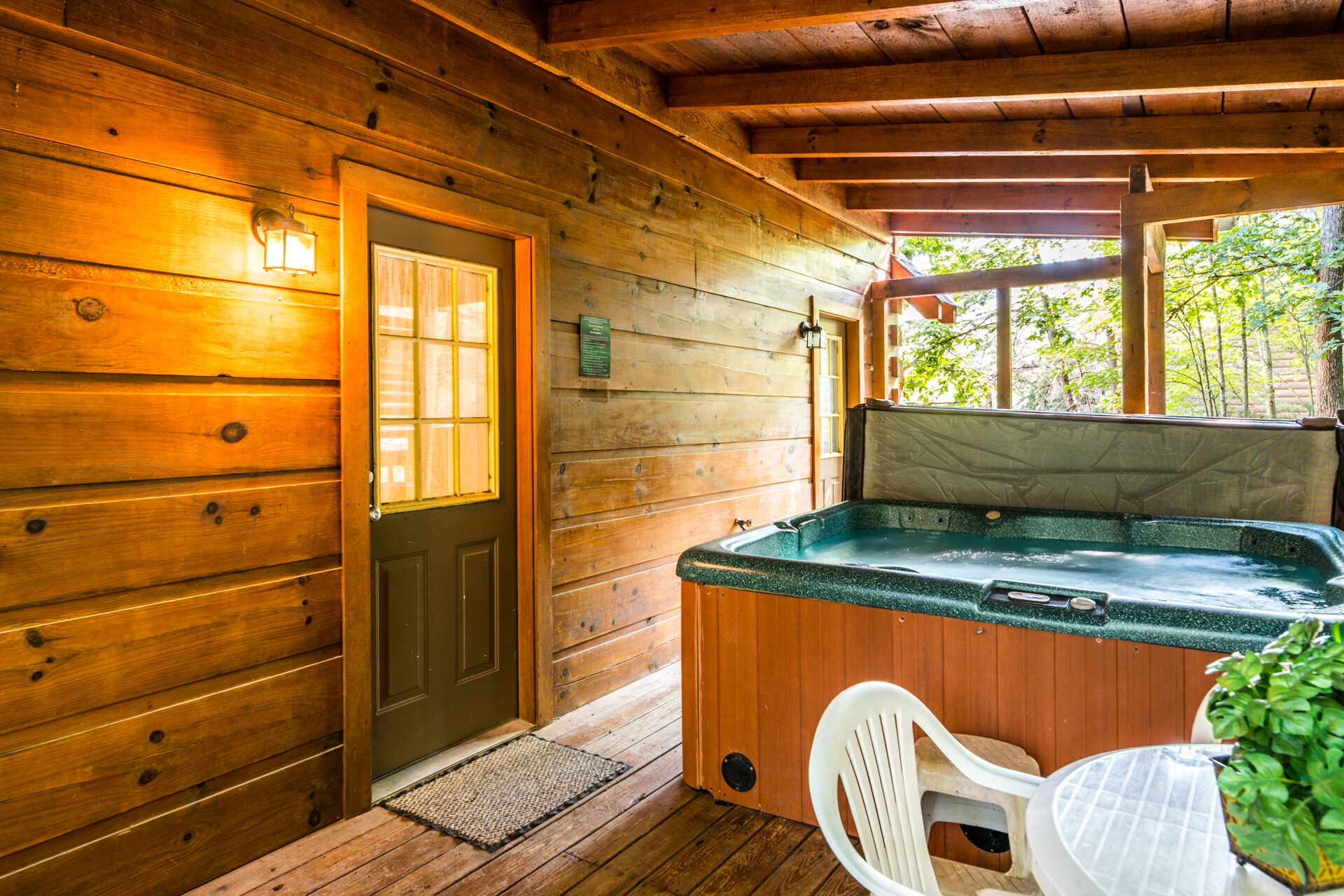 Una cabaña de madera con jacuzzi, una puerta y un ventanal.