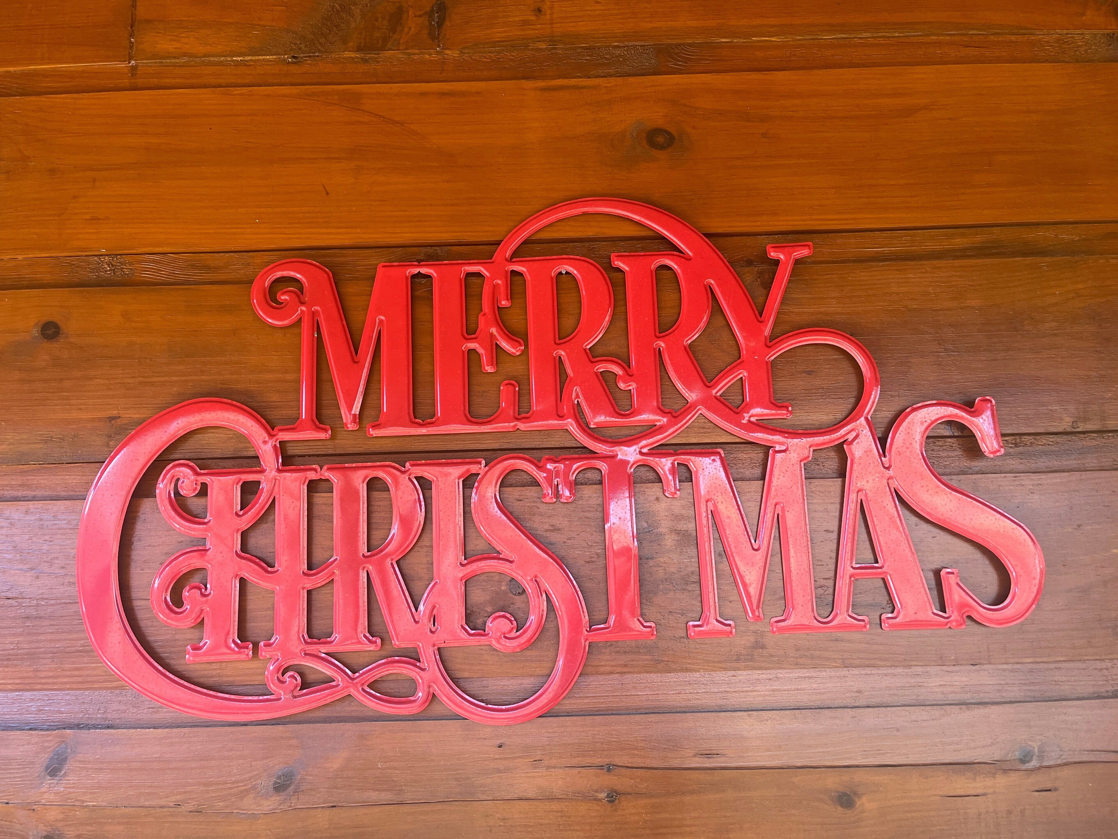 A red "Merry Christmas" sign on a wooden wall.