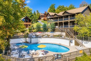 A resort with a swimming pool, outdoor seating, and a building with multiple balconies.