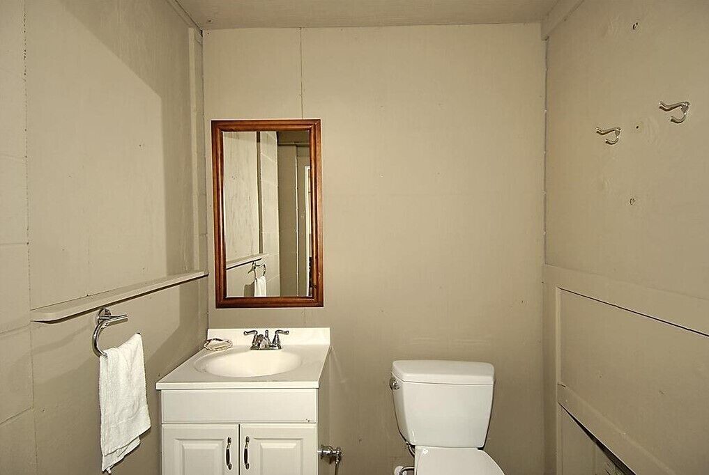 Une petite salle de bain simple, avec un lavabo blanc, un miroir et des toilettes.