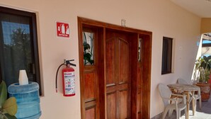 A wooden door with a fire extinguisher mounted on the wall beside it. - Hacienda de Palmas: Room #1 Grande with two queen size beds and sofa bed (La Ribera)