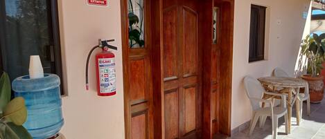 A wooden door with a fire extinguisher mounted on the wall beside it.