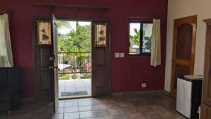 An open doorway leading to a balcony with a view of greenery and a tiled floor. - Hacienda de Palmas: Room #1 Grande with two queen size beds and sofa bed (La Ribera)