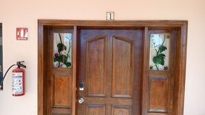 A wooden door with glass panels, a fire extinguisher, and a fire alarm sign on the wall. - Hacienda de Palmas: Room #1 Grande with two queen size beds and sofa bed (La Ribera)