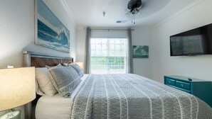 Een slaapkamer met een bed, een televisie, een schilderij en een raam met zonwering.