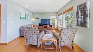 A living room with a sofa, chairs, a coffee table, a TV, and artwork on the walls.