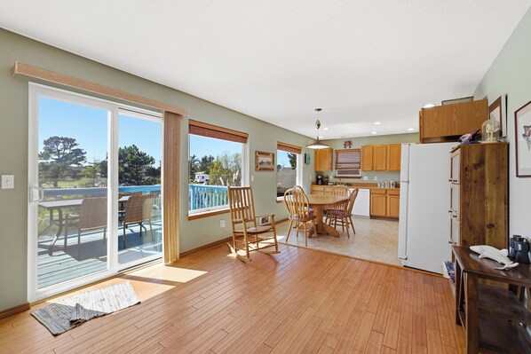 A spacious kitchen with wooden cabinets, a dining area with a table and chairs, and a sliding glass door leading to a deck.