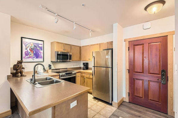 A modern kitchen with stainless steel appliances, a wooden countertop, and a bear statue.
