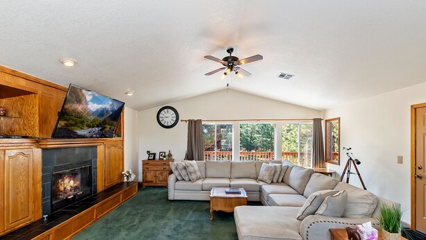 A cozy living room with a fireplace, a large sofa, and a television. - Mountain Crest Getaway: Mountain & Slope Views! Pool Table! Gas Fireplace! Cable! Pet Friendly! WiFi! (Big Bear City)