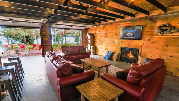 A cozy lounge area with leather sofas, a wooden coffee table, and a fireplace. - Lakefront Cabin #4 The Crappie (Presque Isle)