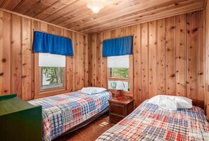 A cabin-style room with two beds, wooden walls, and large windows with blue curtains. - Lakefront Cabin #4 The Crappie (Presque Isle)