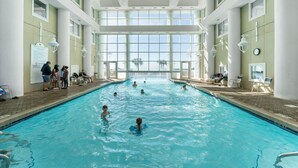 Una piscina interior con paredes de vidrio transparente, múltiples carriles y suelo de baldosas.