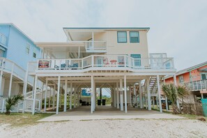 Une maison située en bord de mer, dotée d’une véranda couverte, de plusieurs balcons et d’un escalier menant aux étages supérieurs.