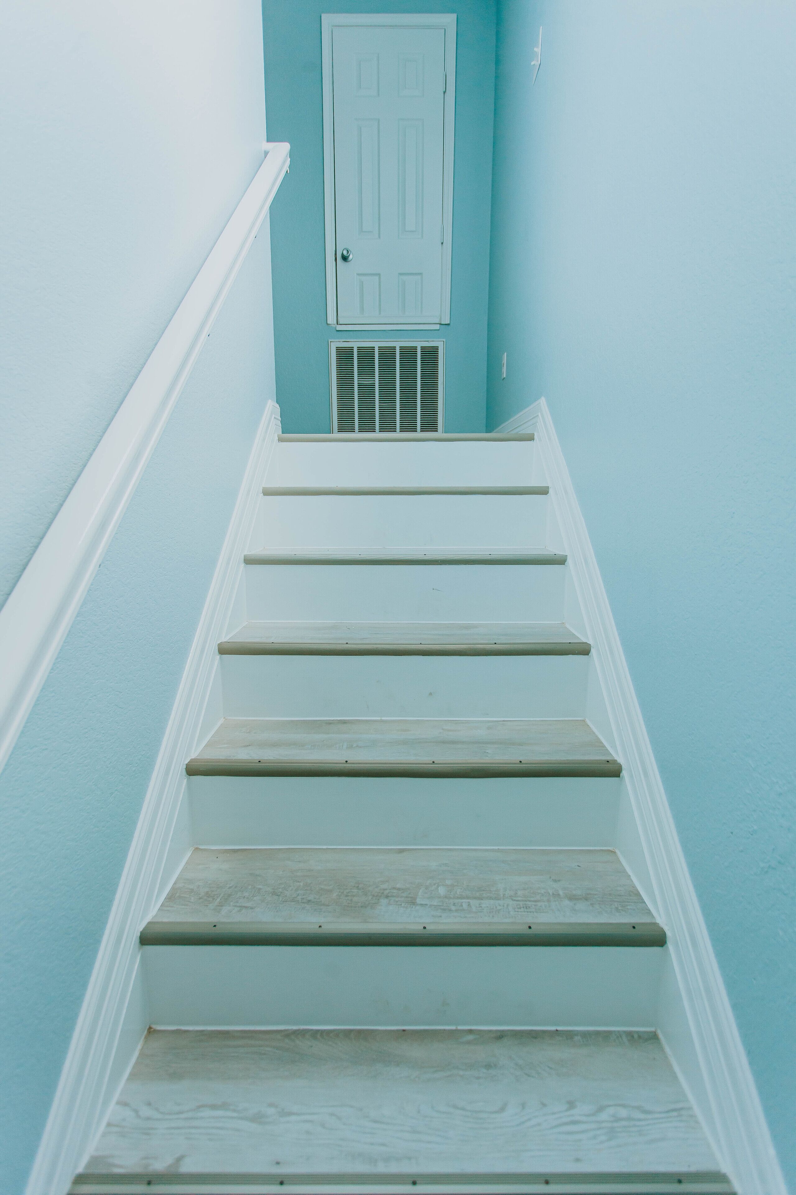 A staircase with white steps and a white door at the top.