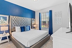 A modern hotel room with a large bed, a flat-screen TV, and a desk. - Beautiful, Newly Renovated Condo! *Steps to Clubhouse/Pool* (Orlando)