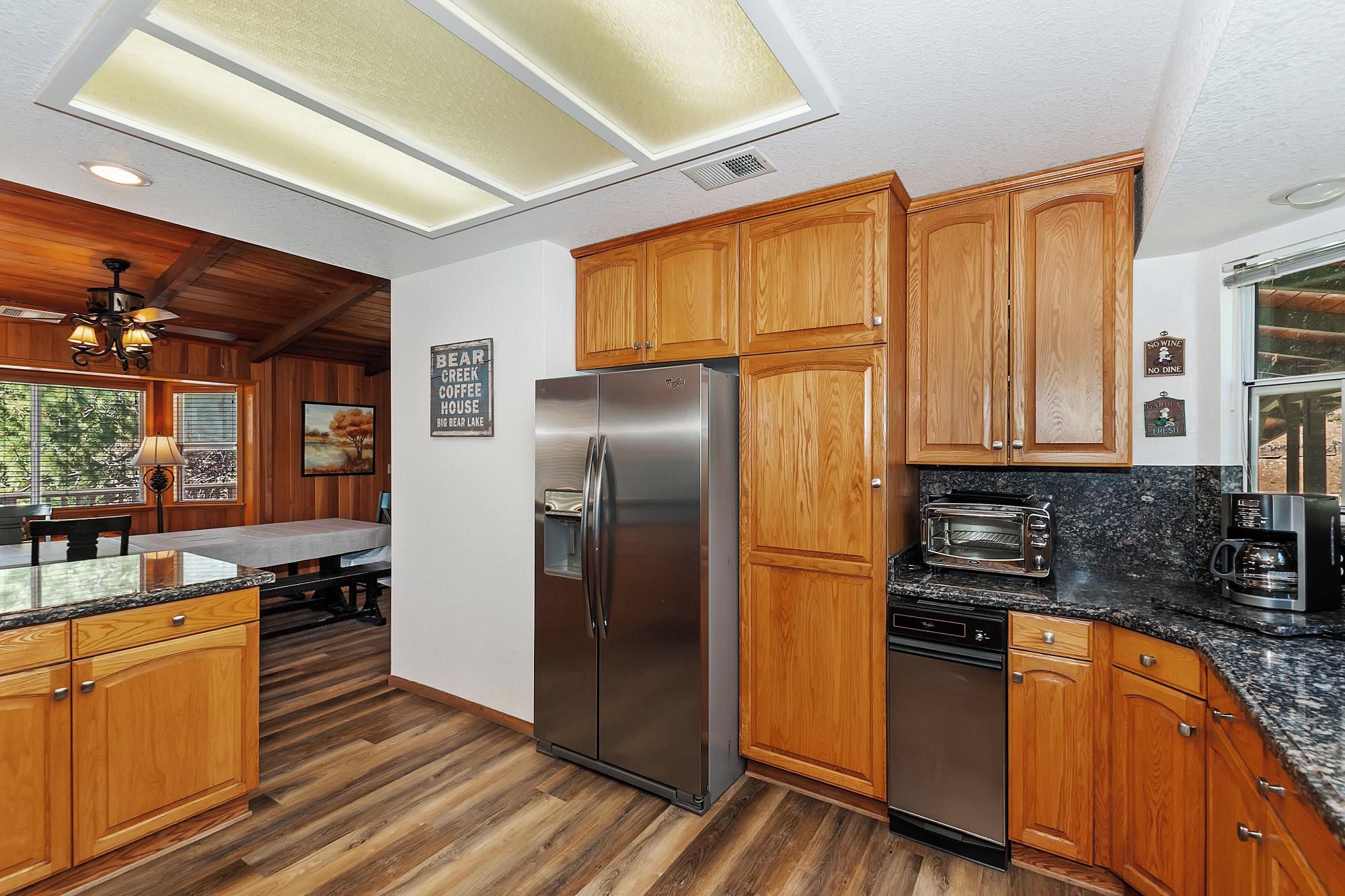 Una cocina con armarios de madera, un refrigerador de acero inoxidable, un tostador y un lavavajillas.