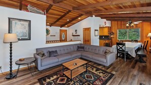 Un salon chaleureux avec un canapé d’angle gris, une table basse en bois et un tapis à motifs.