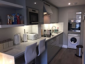 A modern kitchen with a microwave, toaster, sink, and washing machine.