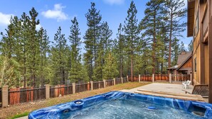 Un jardin avec un jacuzzi, une terrasse en bois et une clôture en bois.