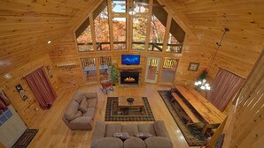 A cozy cabin interior with a fireplace, wooden furniture, and a TV. - Lazy Daze: Theater, Hot Tub, Sauna, Gameroom (Gatlinburg)