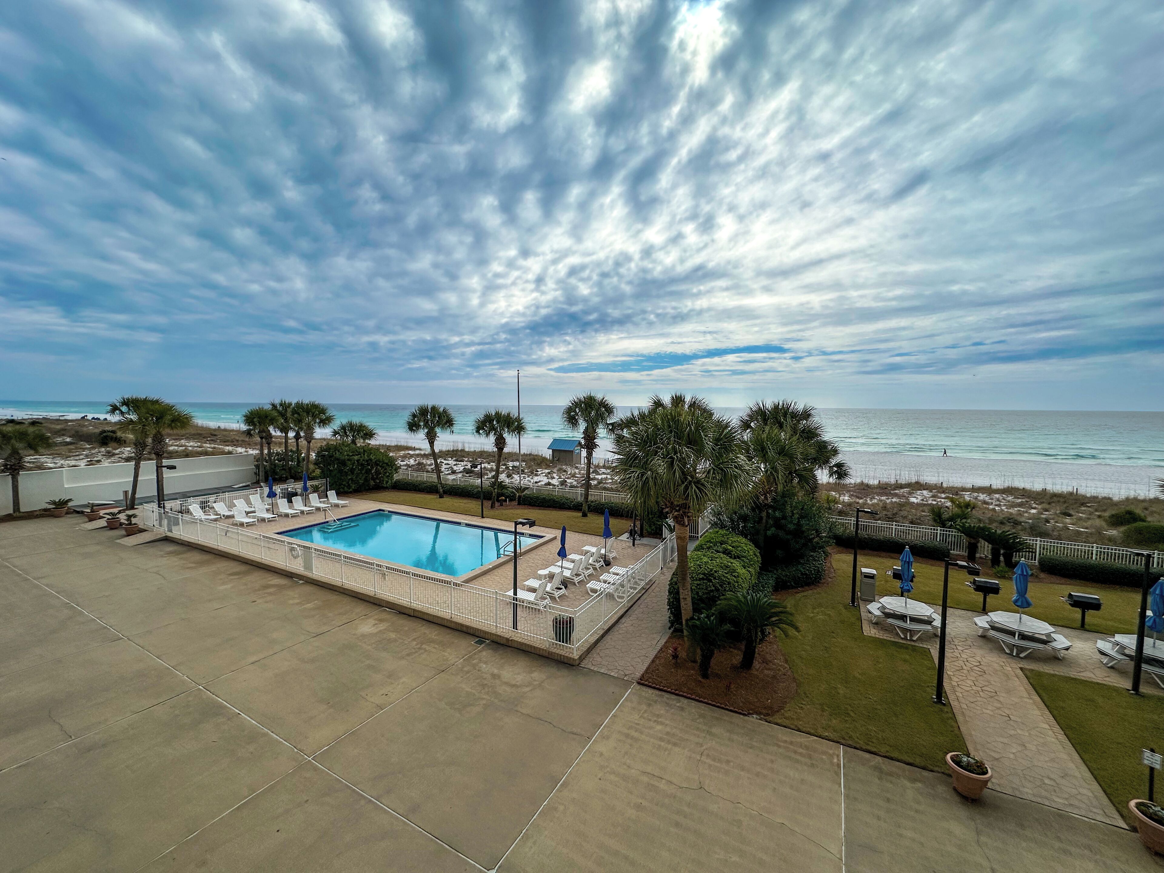 A pool area with lounge chairs and a view of the beach.