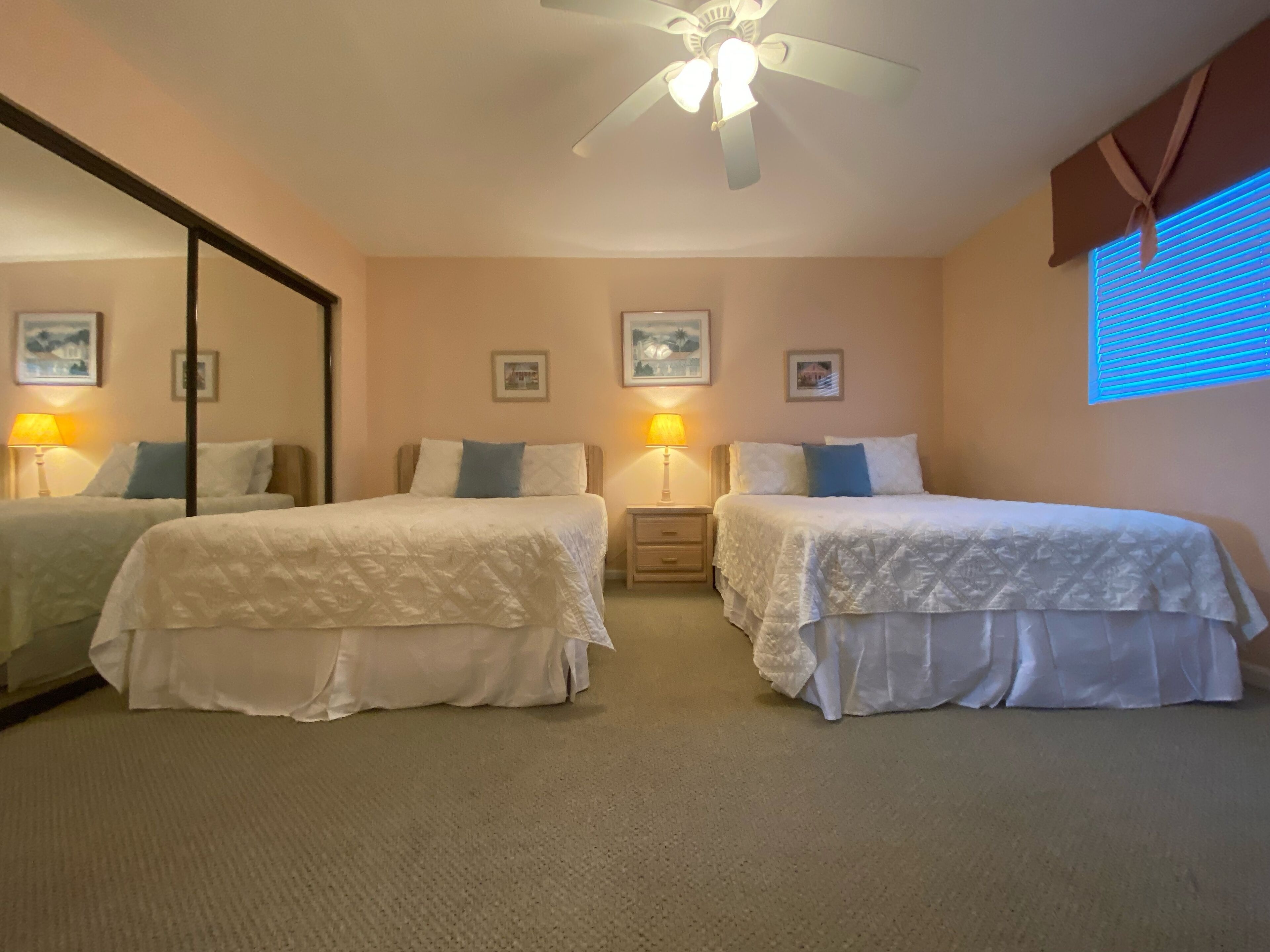 Une chambre d’hôtel avec deux lits simples, un ventilateur de plafond et deux lampes de chevet.
