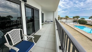 A balcony with a view of the ocean, a pool, and outdoor seating. - "Breakers East 205"~Spacious 2BR/2BA Gulf Front Condo Beach setup included (Destin)