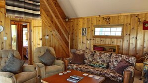 A cozy cabin interior with a sofa, two armchairs, and a wooden coffee table. - Lake Views! Lakefront! BBQ! Internet! Close to the Village! (Big Bear Lake)