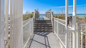 A wooden boardwalk leading to a beach with a clear view of the ocean.