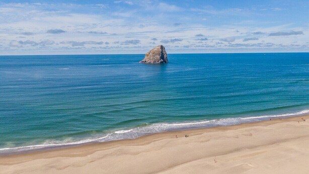 A beach with a large rock formation in the water and a sandy shore. - Seaside Splendor - large home, fantastic views very, close to beach (Pacific City)
