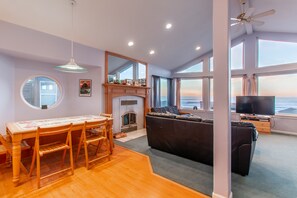 Relax in this inviting space with a fireplace, dining table, and sofa, offering a view of the outdoors.