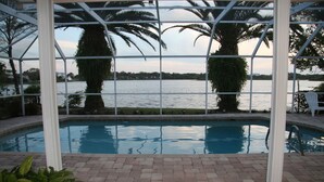 A pool area with a view of a lake, surrounded by palm trees and a pergola structure. - Key West Style Waterfront, Private Pool, WiFi, Close to Village & Beaches Pet OK (Safety Harbor)