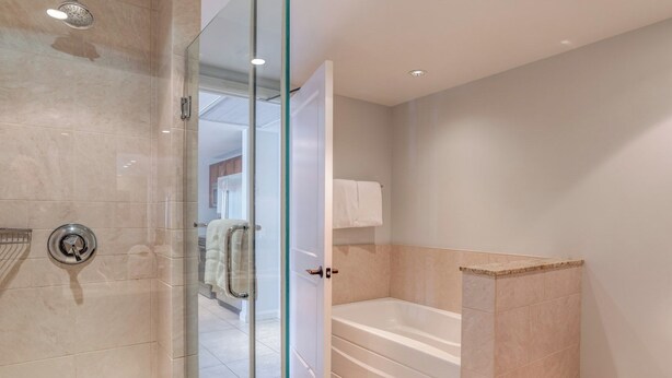 A modern bathroom with a glass-enclosed shower, a bathtub, and a glass door. - Honua Kai | Ocean View 2 BR | Large Floorplan | Car Incl. w/ 6+ Nights | HKH-412 by KBM (Lahaina)