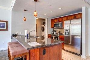 A modern kitchen with a central island, stainless steel appliances, and wooden cabinetry.