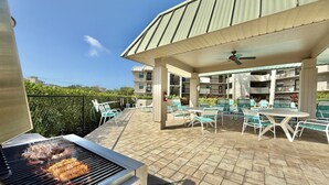 An outdoor patio with a grill, lounge chairs, and a covered seating area.
